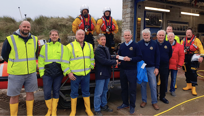 Bude Rotary Club president Rob Cox and several Rotary Club members with Michael Walker and other members of the RNLI team after a recent training session in very challenging conditions in the water off Summerleaze Beach