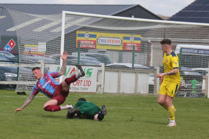 Launceston midfielder goes over in the box as Wendron goalkeeper Zach Telling collects.