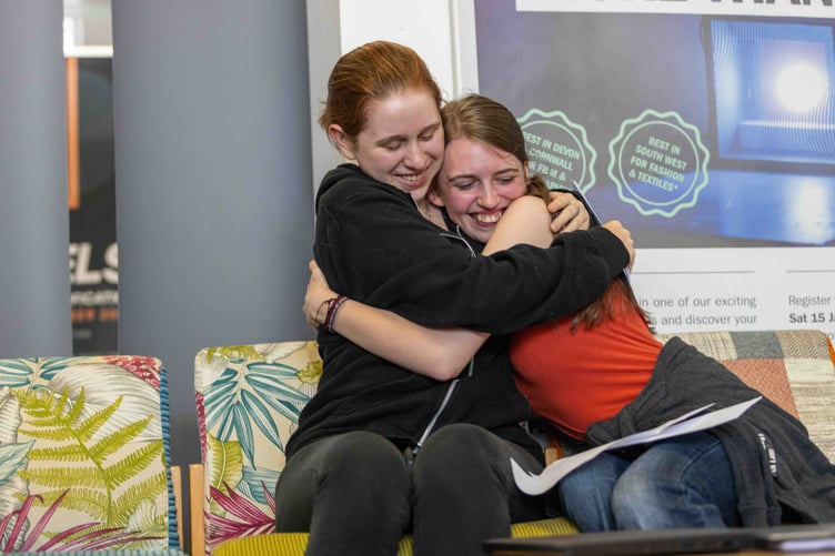 Two students embrace each other in celebration after opening their results