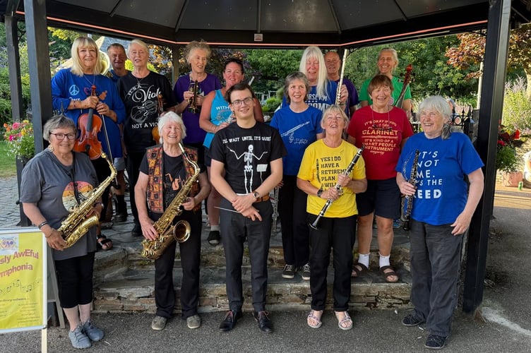 Pictured here with their instruments, the players in the Seriously AwEful Symphonia are (left to right): Sally Batchelor (saxophone), Vicki Rigby (violin), David West (French horn), Maggie Strange (viola), Daphne Moore (saxophone), Sheena King (trumpet), Claire Deithrich (flute), Fergal Donnellon (conductor), Jane Tily (flute), Anne Henderson (alto flute), Kath Richardson (clarinet), Alan Read (piano), Andrea Curtis (clarinet), Rowan Fawdon (cello) and Lesley Carter (oboe).