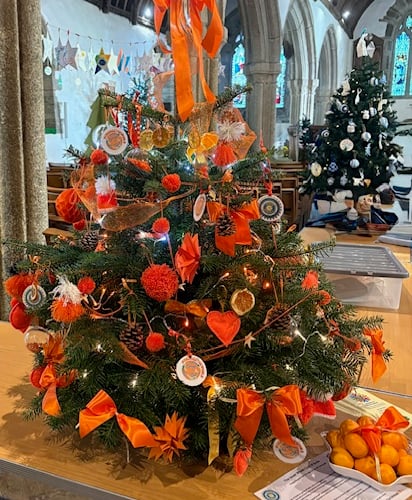 The orange themed Christmas tree decorated by Bude Inner Wheel for the Christmas Tree Festival at St Marwenne’s Church in Marhamchurch