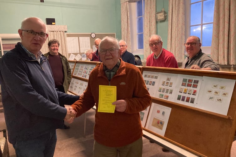 Viv Sandercock being presented with a certificate of appreciation by Launceston Stamp Club chairman Barry Mudie with club members looking on