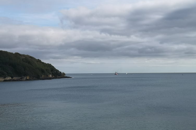 A ship moving away from Pendennis Point with smoke rising from it